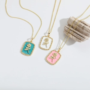 Detailed macro view of 14k gold plated rectangular rose pendants in three enamel colors