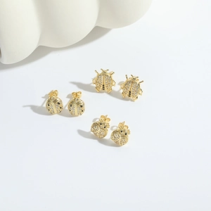 Golden ladybug stud earrings set with white zircon and black gemstone accents