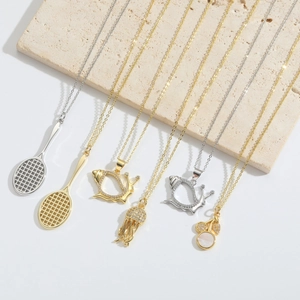 Detalle de collares modernos con colgantes de raqueta de tenis, caracol y medusa