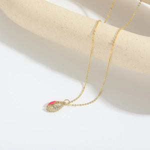 Close-up of golden rugby-style pendant with pink enamel coating and sparkling white zirconias