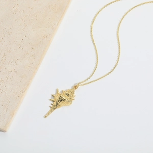 Elegant gold shell pendant necklace with a textured marine design on a stone background