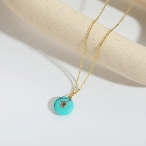 Minimalist gold necklace with turquoise circle pendant and purple crystal stone