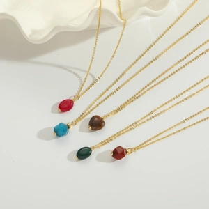 Detailed macro view of heart and oval natural stone pendants with gold chains on shell