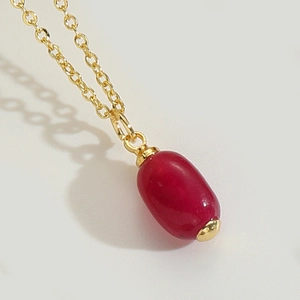 Minimalist gold necklace with an oval ruby red gemstone pendant in a polished finish