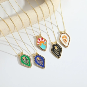 Gold Hamsa shield necklace with enamel colors and zircon accents on beige display