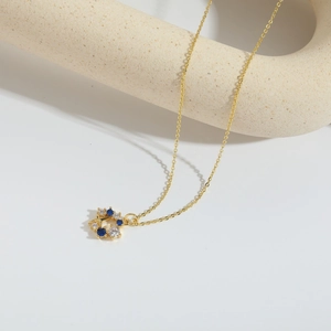 Elegant gold star pendant necklace with blue and clear gems on a white background