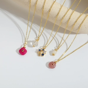 Close-up of five colorful gemstone necklaces displayed on an elegant stone jewelry stand