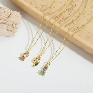 Trois colliers dorés avec de mignons pendentifs en résine et des gemmes colorées