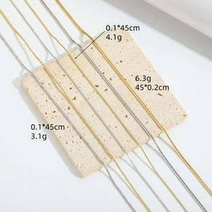 Collares minimalistas de oro y plata de 45 cm presentados sobre una base de piedra