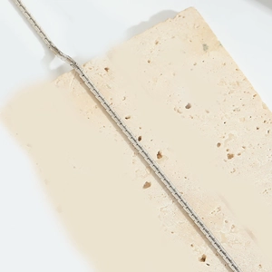 Primer plano macro de collar de cadena box plateada sobre piedra beige con eslabones
