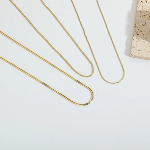 Tres elegantes collares minimalistas dorados con diferentes texturas sobre blanco