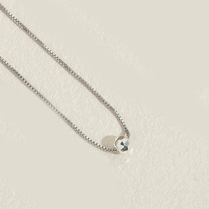 Détail d'un collier chaîne box argentée avec pendentif sphère géométrique à facettes brillant
