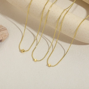 Trois colliers dorés à mailles vénitiennes et pendentifs géométriques sur supports en pierre