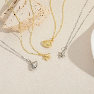 Chic gold and silver starfish and seashell pendant necklaces on a sandy beach setting