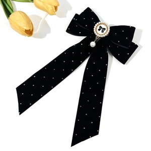 Détail de la pince à cheveux noeud en velours noir à pois blancs et pendentif perle