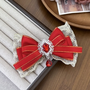 Detail of red bow hair clip with lace trim, gold edges and crystal gemstone center