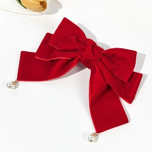 Elegant red velvet bow hair clip with white pearl pendants on a minimalist background