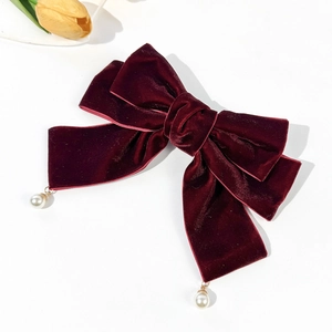 Close-up of vintage burgundy velvet bow hair clip with elegant pearl pendants and soft texture