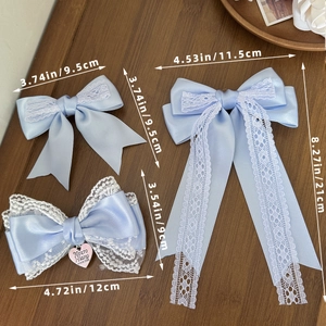 Three elegant light blue satin bow hair clips in various sizes on a wooden background