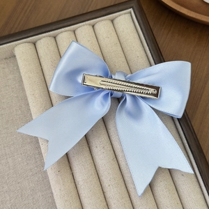 Elegant light blue satin double bow hair clip on a beige velvet display box