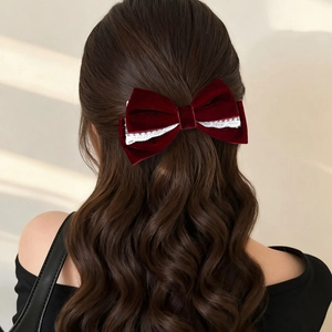 Detail showing a wine red velvet bow hair clip with lace trim on long wavy hair