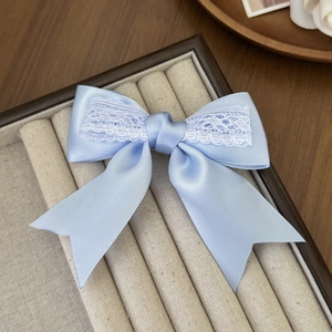 Detail of light blue satin bow hair clip with white lace trim on a jewelry display box