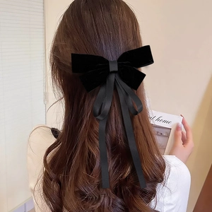 Detail of a large black velvet bow hair clip with elegant long ribbons on wavy hair
