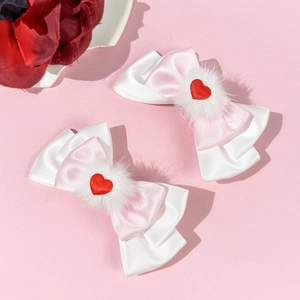 Détail de barrettes à nœuds roses avec pompons blancs et cœurs rouges pour filles