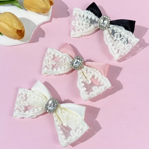 Barrettes noeuds en dentelle avec strass en noir, rose et beige sur fond rose doux