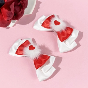 Détail de barrettes à nœuds rouges avec pompons blancs et cœurs rouges pour la Saint-Valentin
