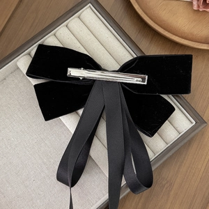 Elegant French vintage black velvet bow hair clip with long streamers on a beige display