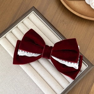 Detail of burgundy velvet bow hair clip with white lace trim in a beige jewelry gift box