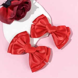 Paire de nœuds à cheveux en satin rouge avec cœurs sur un support décoratif romantique