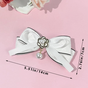 Détail d'une élégante pince à cheveux à nœud avec fleur de camélia et pendentif perle