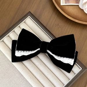 Close-up of black velvet bow hair clip with white lace trim on a jewelry display box