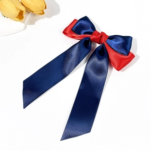 Detailed view of the contrast color satin bow hairpin with long flowing ribbons in navy and red