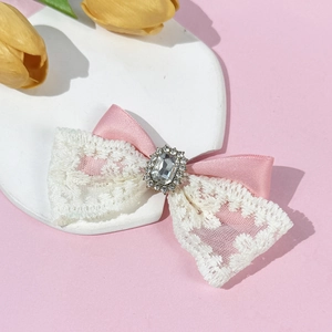 Détail de pince à cheveux avec ruban rose, dentelle blanche et centre en strass luxe