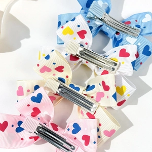 Close-up of four colorful heart pattern ribbon hair clips with stainless steel duckbill clips