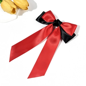 Detail of red and black satin bow hairclip with long ribbons and smooth silk texture
