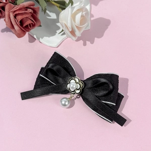 Détail du nœud en satin noir avec fleur de camélia et pendentif en perle élégante