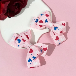 Pink heart pattern bow hair clips set on a decorative white stone with a red rose