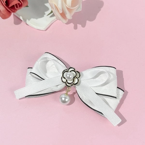 Vue détaillée de la barrette nœud en soie blanche avec fleur de camélia et perle pendante