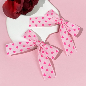 Nahaufnahme von rosa Haarschleifen mit Herzmuster auf einer weißen Dekoplatte aus Stein