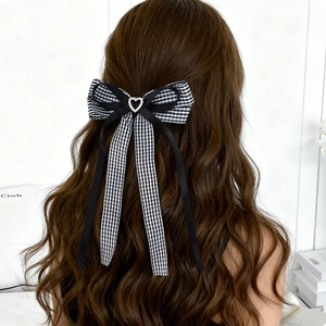 Dettaglio di un fermaglio per capelli a quadretti con strass a cuore e lunghi nastri neri