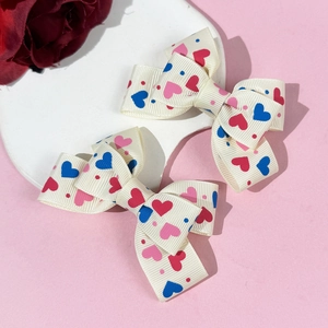 Detail of white ribbon hair clips with colorful heart patterns and textured fabric