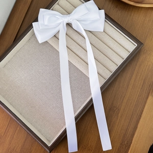 Detail view of rectangular wooden jewelry tray with white ribbon bow and beige fabric slots