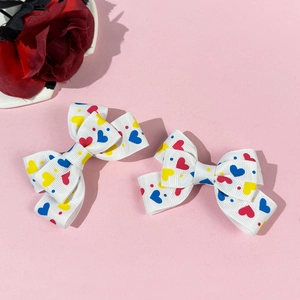 Detail of white grosgrain hair clips with colorful heart patterns and red rose accent