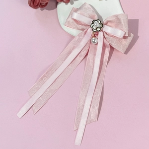 Détail de pince à cheveux en dentelle rose avec breloque camélia et pendentifs perles