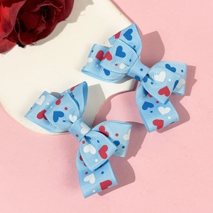 Detail of light blue bow hair clips with red and white heart patterns on pink background