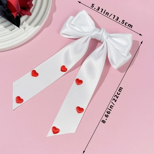 Vue détaillée de la taille d'un nœud papillon en satin blanc avec cœurs rouges pour cheveux